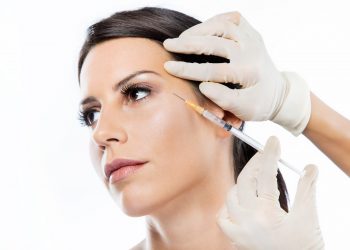 Portrait of beautiful young woman getting botox cosmetic injection in her face over white background.